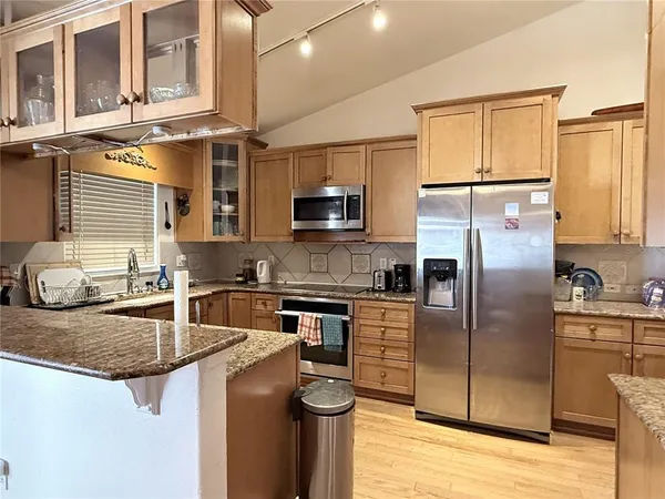 a kitchen with stainless steel appliances granite countertop a refrigerator a stove a sink and a microwave