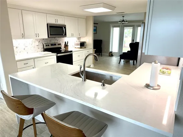 a kitchen with stainless steel appliances a stove a sink a microwave and white cabinets