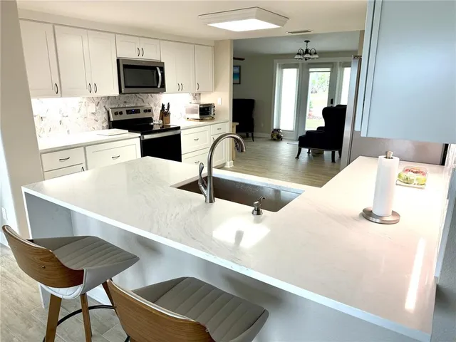a kitchen with stainless steel appliances a stove a sink a microwave and white cabinets