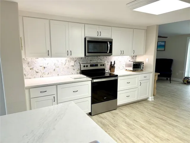 a kitchen with white cabinets and stainless steel appliances