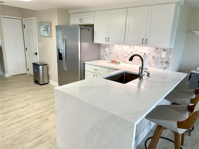 a kitchen with stainless steel appliances kitchen island a sink a refrigerator and cabinets