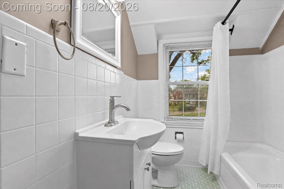 429 Moran Road Grosse Pointe, MI 48236 - Photo 23 of 36 Bathroom featuring a vanity with an integrated sink, polished chrome faucet, white square tile wainscoting, and a built-in tub with a shower