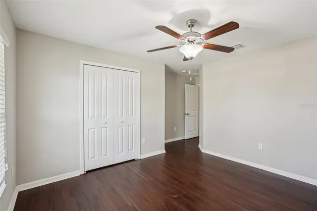 an empty room with wooden floor fan and windows