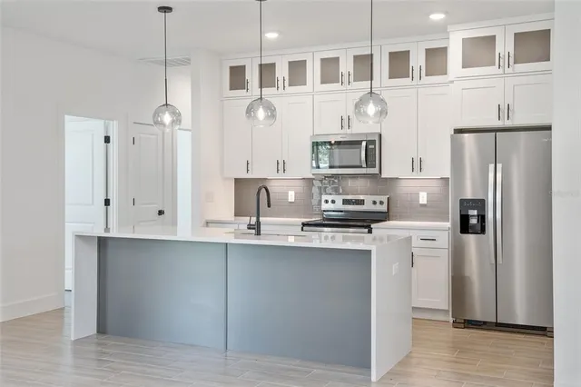 a kitchen with stainless steel appliances granite countertop a refrigerator a stove a sink and a microwave