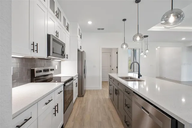 a kitchen with stainless steel appliances granite countertop a sink a stove and a refrigerator