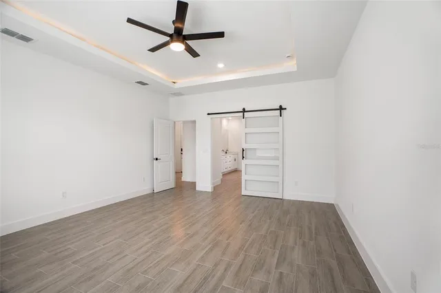 an empty room with wooden floor chandelier fan and windows
