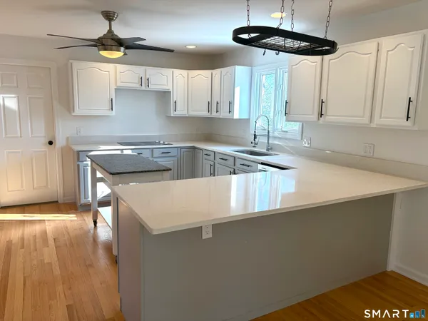 a kitchen with stainless steel appliances granite countertop a sink a stove and a wooden floors