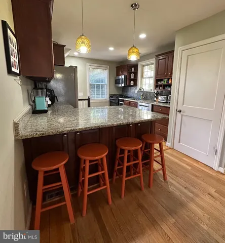a kitchen with stainless steel appliances granite countertop a table chairs refrigerator and sink