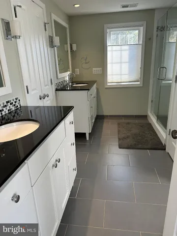 a spacious bathroom with a granite countertop sink a mirror and a bathtub