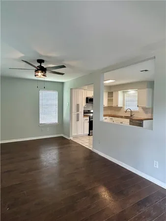 an empty room with wooden floor and a kitchen