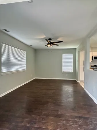 an empty room with wooden floor cabinet and windows