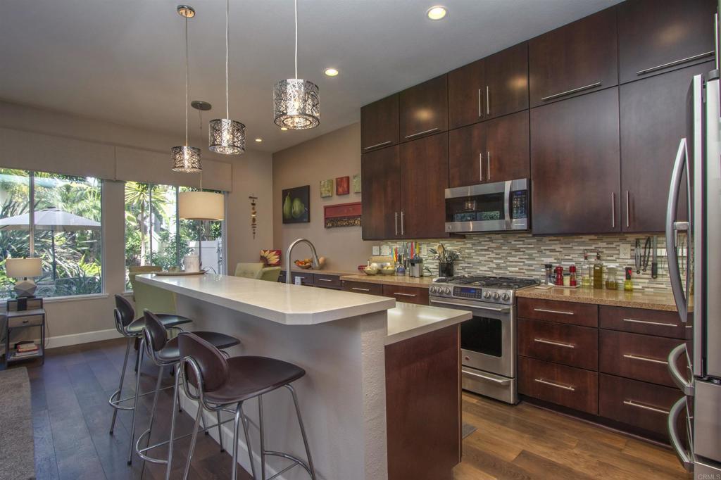 1684 Robin Place Carlsbad, CA 92011 - Photo 7 of 24 a kitchen with a stove a sink a microwave a dining table and chairs