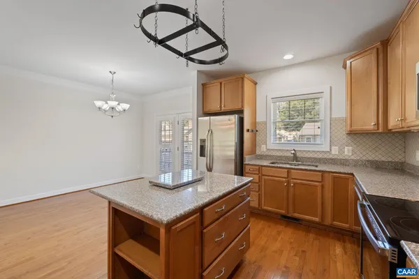 a kitchen with stainless steel appliances granite countertop a sink dishwasher a stove a refrigerator and island with wooden floor