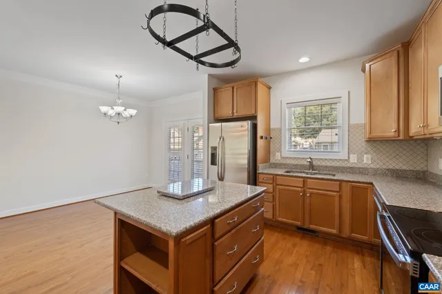 a kitchen with stainless steel appliances granite countertop a sink dishwasher a stove a refrigerator and island with wooden floor