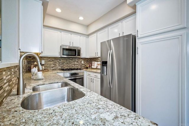 a kitchen with granite countertop a refrigerator stove and sink