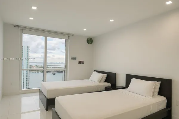 a bedroom with two large bed and a large window