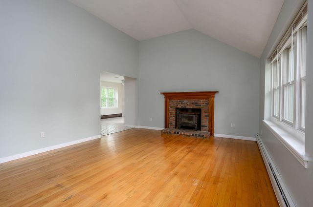 a view of an empty room with a window and fireplace
