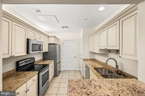 a kitchen with stainless steel appliances granite countertop a stove top oven a sink dishwasher and cabinets with wooden floor