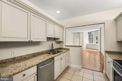 a kitchen with granite countertop a sink a stove and cabinets