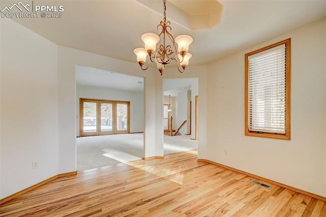 15091 Ridgefield Lane Colorado Springs, CO 80921 - Photo 12 of 35 Unfurnished dining area featuring french doors, a chandelier, and hardwood / wood-style floors