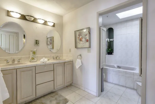 a bathroom with a double vanity sink mirror and bathtub