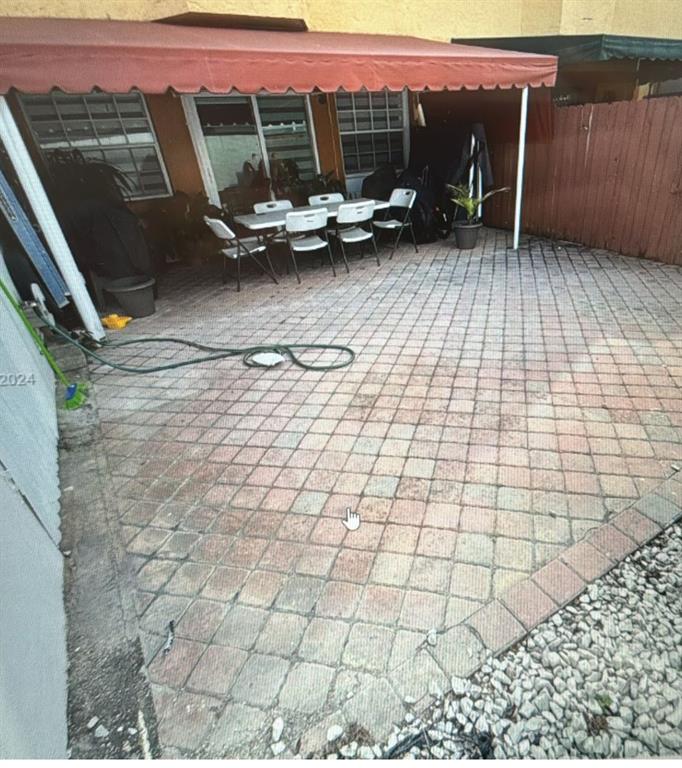 11821 Southwest 18th Street, Unit 223 Miami, FL 33175 - Photo 30 of 31 a view of a patio with table and chairs with wooden floor and fence
