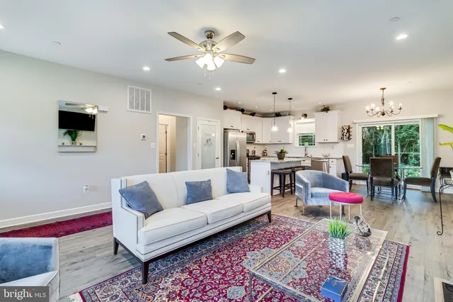 a living room with furniture kitchen view and a chandelier