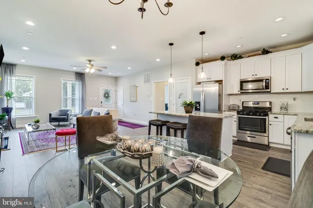a living room with stainless steel appliances kitchen island granite countertop a dining table chairs refrigerator and sink