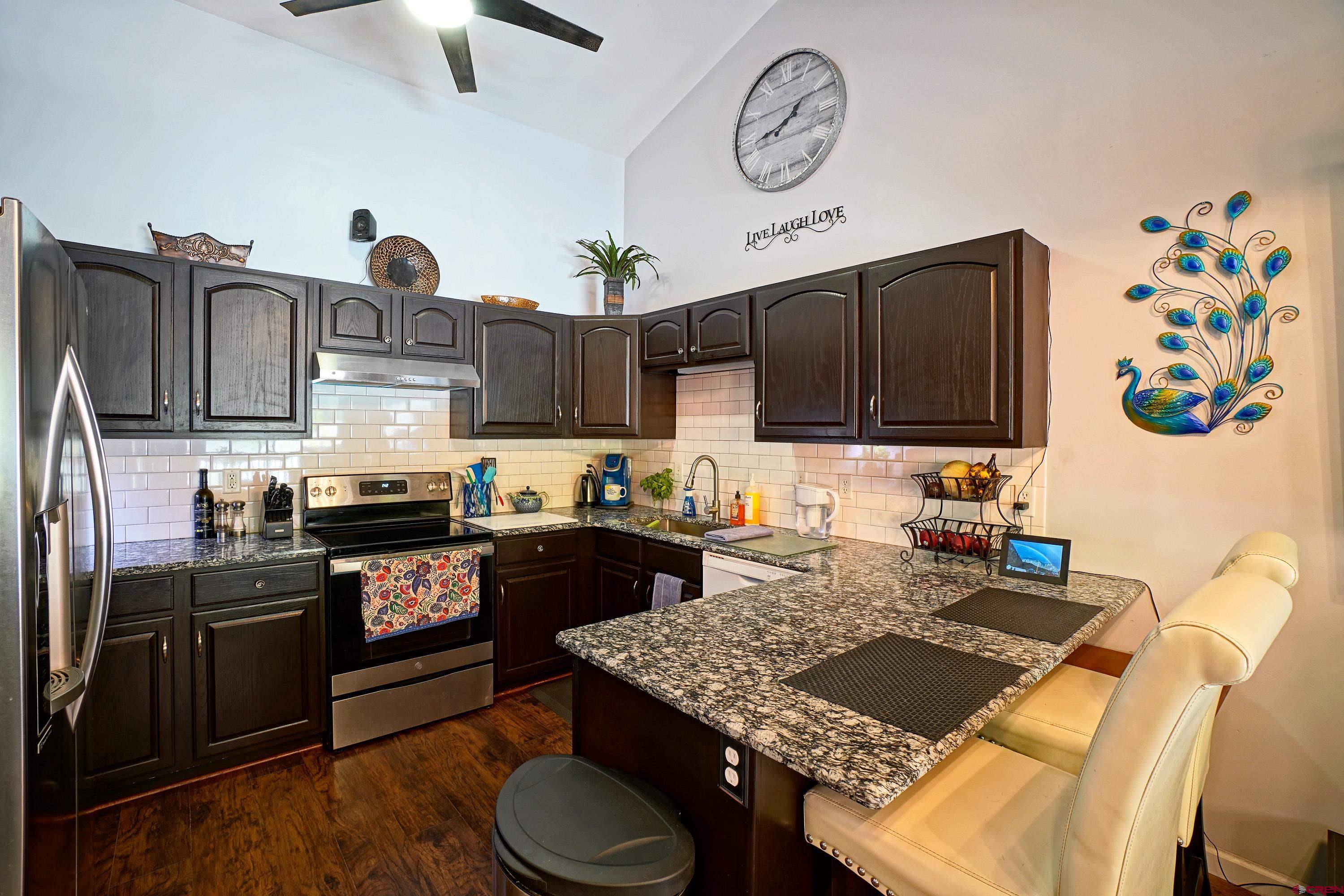 1316 Main Street Ouray, CO 81427 - Photo 14 of 39 a kitchen with stainless steel appliances granite countertop a stove top oven a sink a dining table and chairs with wooden floor