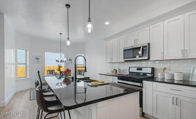 a kitchen with stainless steel appliances granite countertop a table chairs sink and cabinets