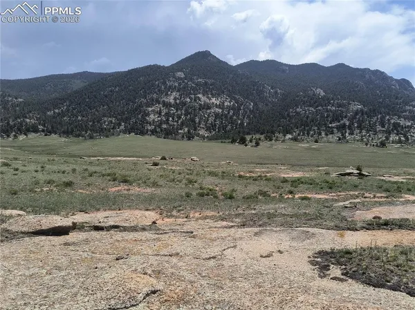 a view of dirt field with mountains in the background