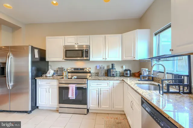 a kitchen with stainless steel appliances granite countertop a stove a sink dishwasher and a refrigerator