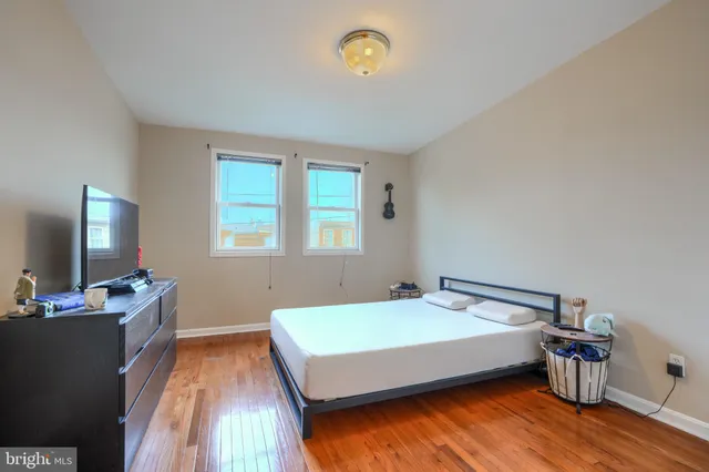 a bedroom with a bed and flat tv screen on the dresser
