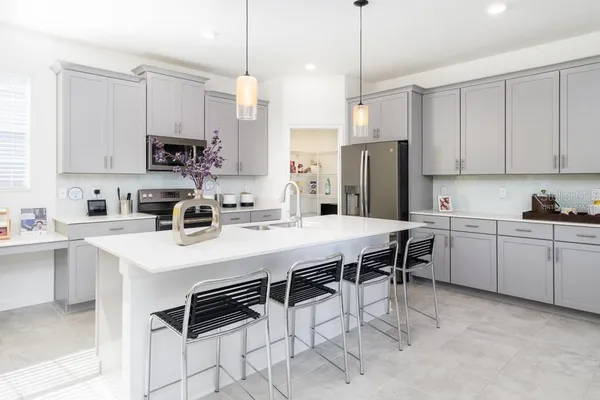 a kitchen with stainless steel appliances kitchen island a table chairs microwave and cabinets