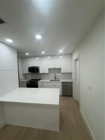 a large white kitchen with a white stove top oven and white cabinets