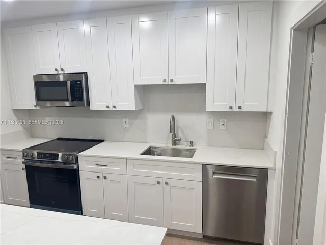 a kitchen with appliances a sink and cabinets