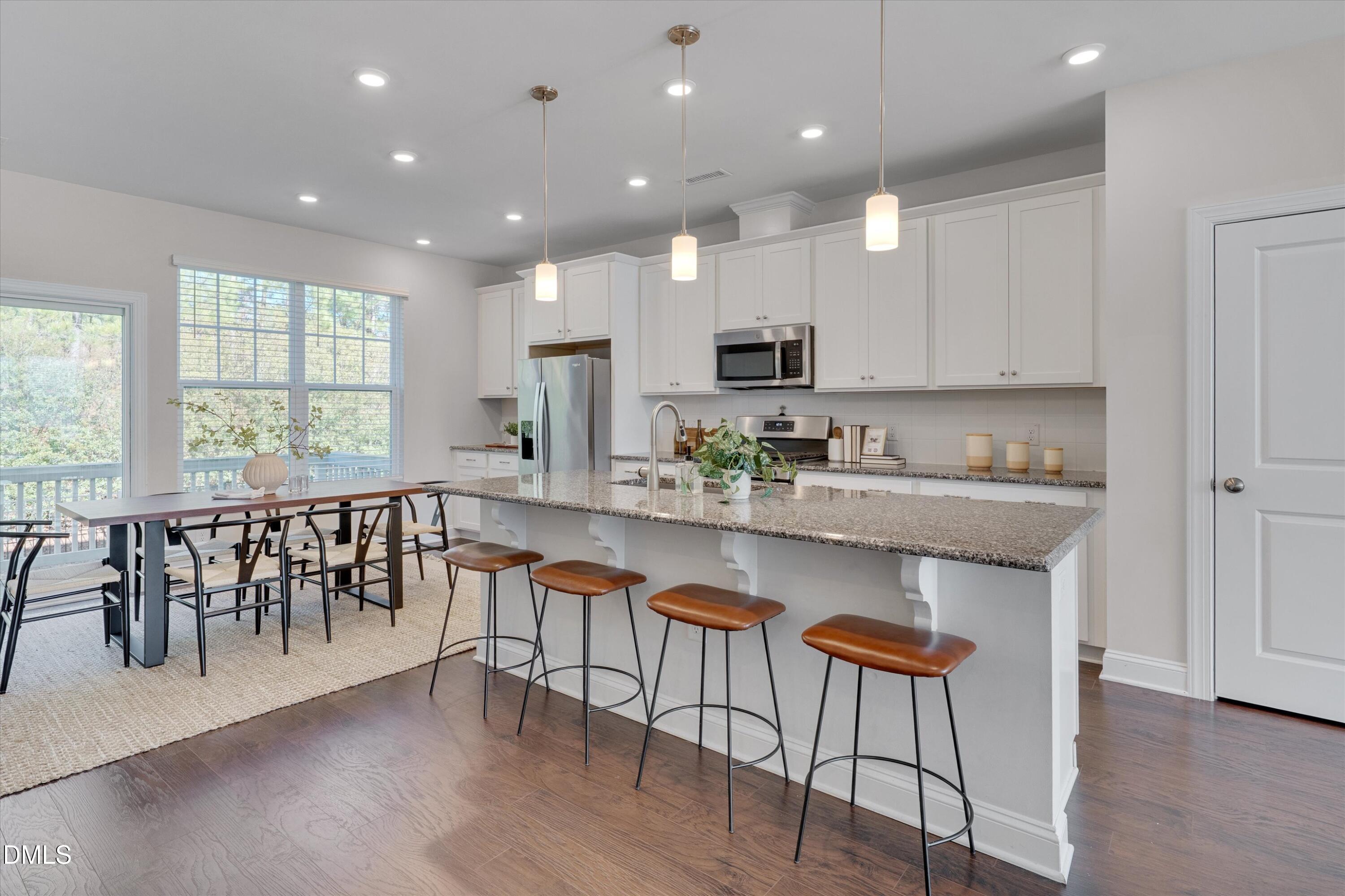2819 Dallas Valley Lane Apex, NC 27502 - Photo 12 of 38 a kitchen with stainless steel appliances granite countertop a stove top oven a dining table and chairs with wooden floor