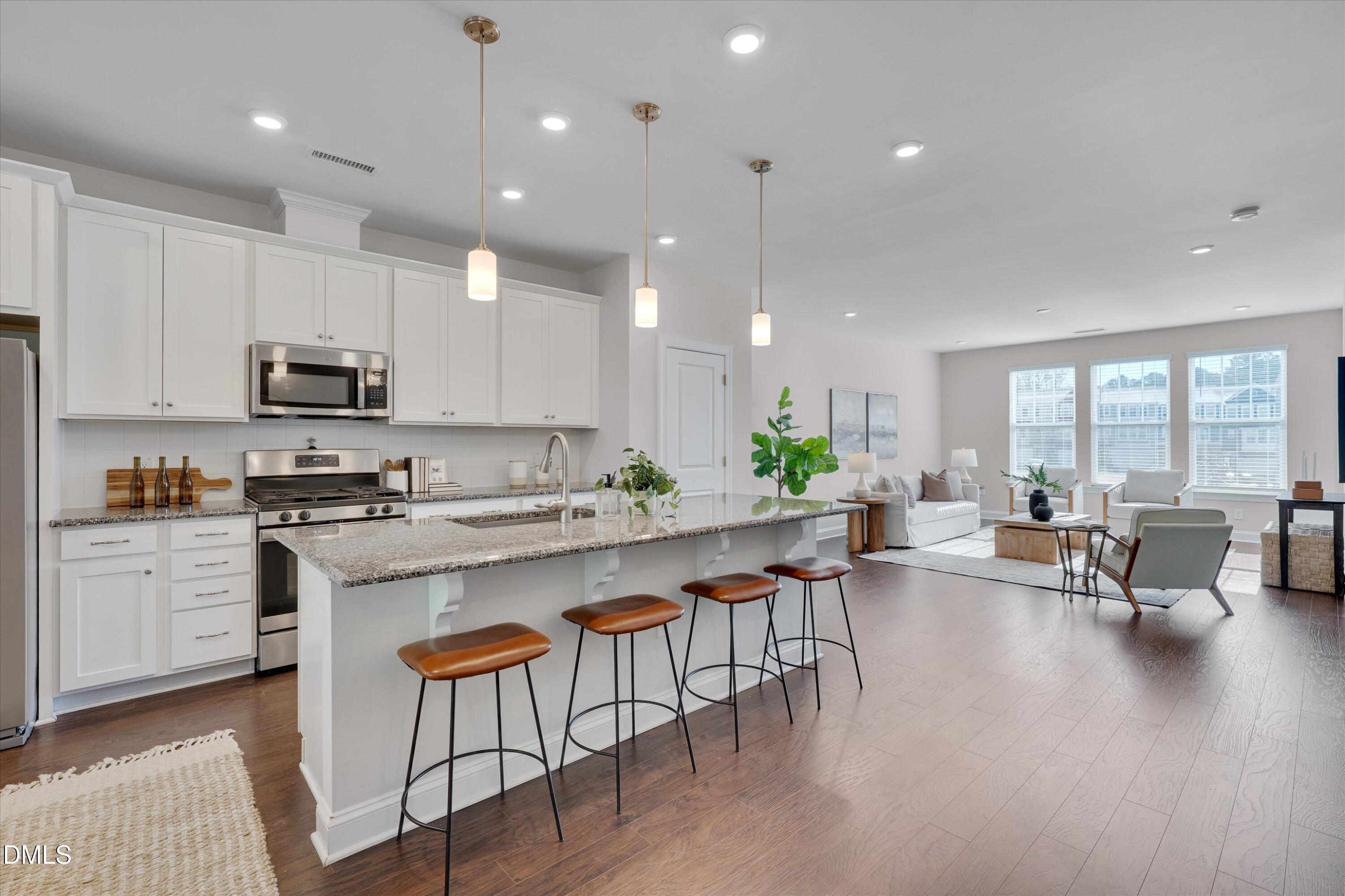 2819 Dallas Valley Lane Apex, NC 27502 - Photo 14 of 38 a kitchen with stainless steel appliances granite countertop a stove a sink a microwave a dining table and chairs with wooden floor