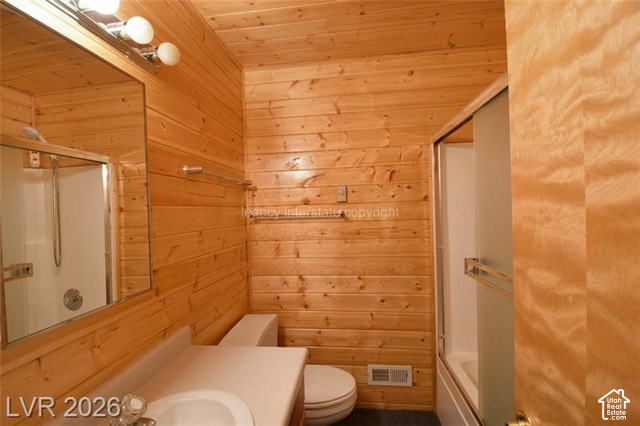 1129 Ponderosa Road, Unit 40 Hatch, UT 84735 - Photo 28 of 47 Wood-paneled walls, vanity with integrated sink, wall-mounted mirror, three-bulb vanity light fixture, and enclosed shower with sliding glass door