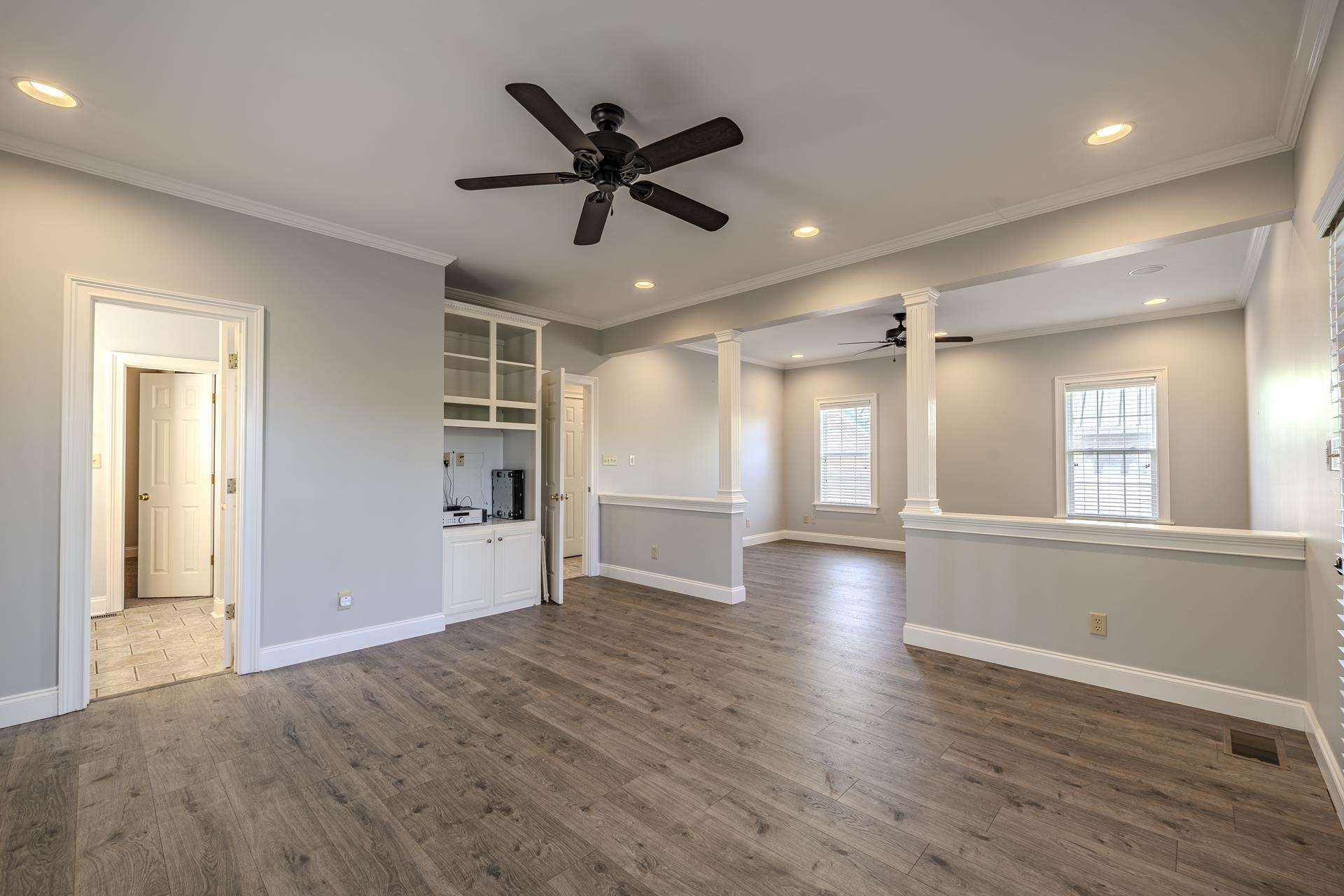 9 Mountain View Iuka, MS 38852 - Photo 14 of 32 Unfurnished living room featuring a ceiling fan, ornate columns, dark wood-style floors, recessed lighting, and crown molding