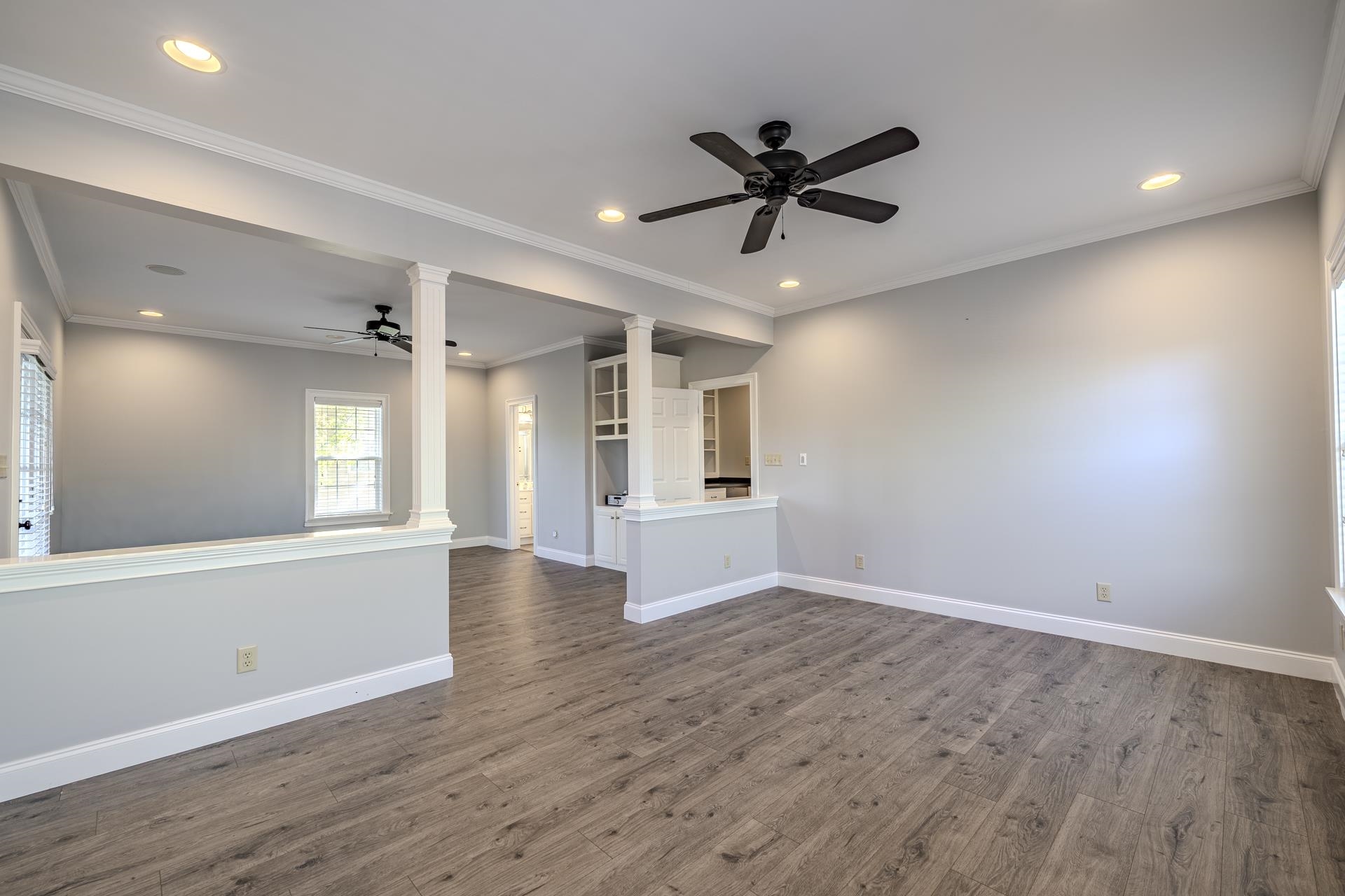 9 Mountain View Iuka, MS 38852 - Photo 16 of 32 Unfurnished living room featuring a ceiling fan, dark wood finished floors, crown molding, recessed lighting, and decorative columns