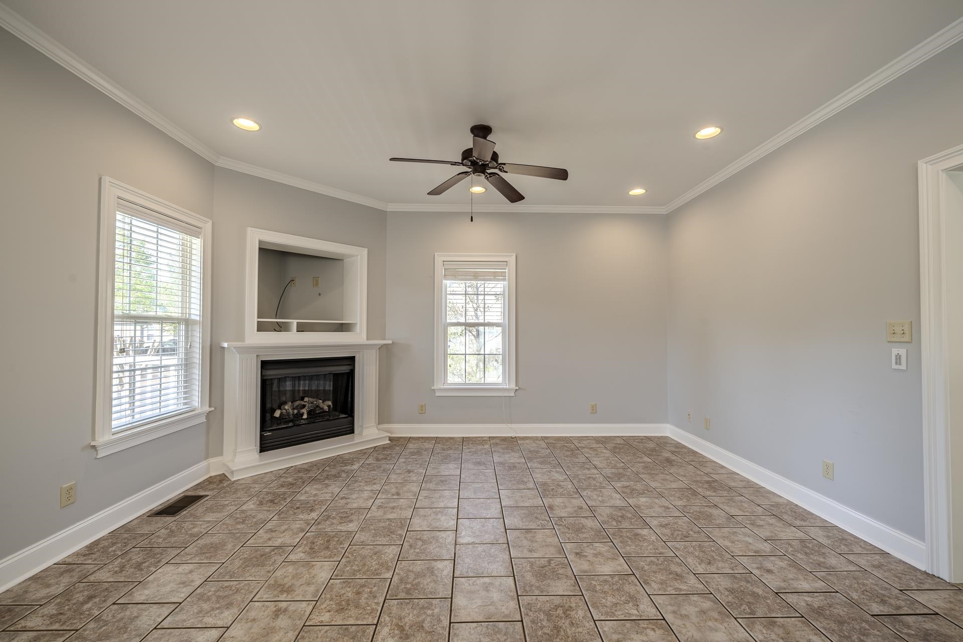9 Mountain View Iuka, MS 38852 - Photo 6 of 32 Unfurnished living room featuring a fireplace with raised hearth, a ceiling fan, recessed lighting, and ornamental molding