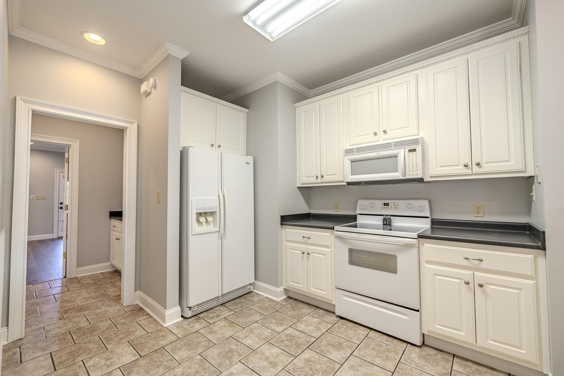 9 Mountain View Iuka, MS 38852 - Photo 7 of 32 Kitchen featuring dark countertops, white appliances, crown molding, and white cabinets