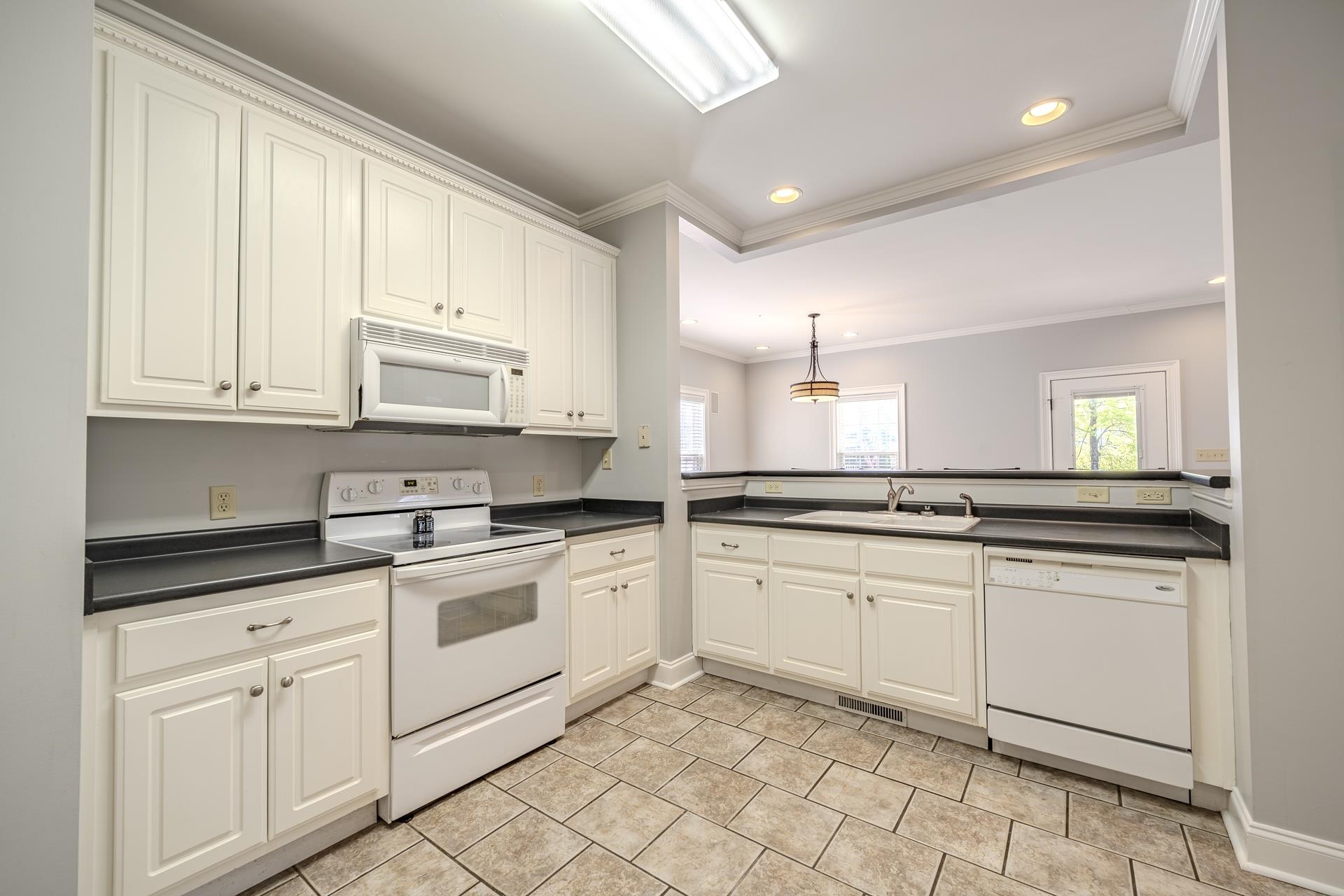 9 Mountain View Iuka, MS 38852 - Photo 8 of 32 Kitchen featuring white appliances, ornamental molding, dark countertops, white cabinets, and hanging light fixtures