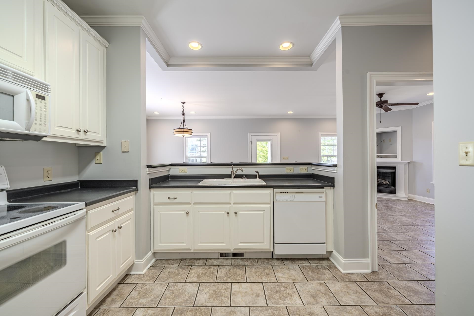 9 Mountain View Iuka, MS 38852 - Photo 9 of 32 Kitchen with white appliances, white cabinets, dark countertops, a fireplace with raised hearth, and recessed lighting