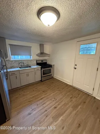 a kitchen with granite countertop a stove a sink and a wooden floors