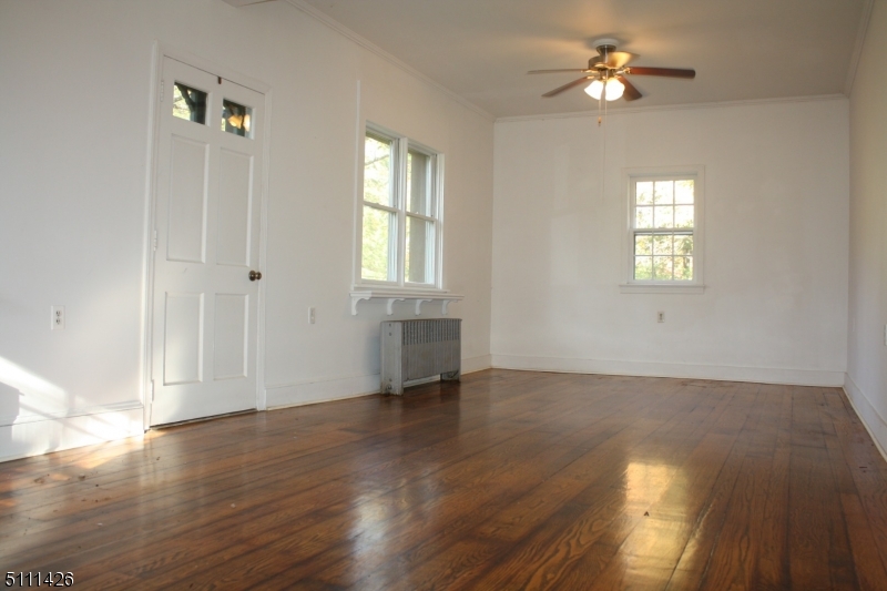 245 Millbrook Road Washington, NJ 07882 - Photo 12 of 34 an empty room with wooden floor chandelier fan and windows