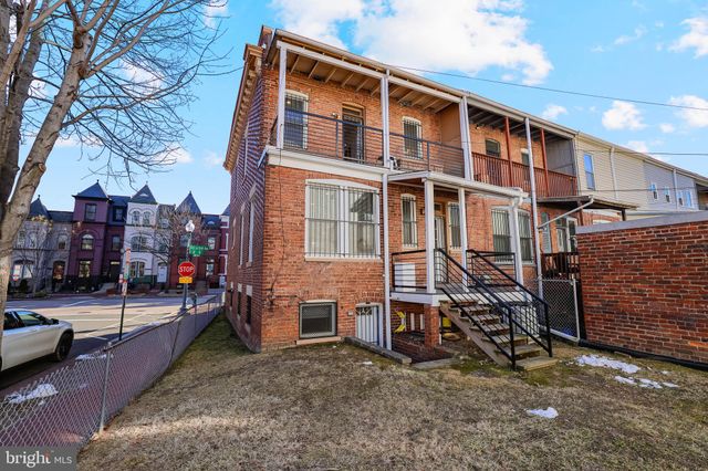 a view of a blue house with a cars park side of a road