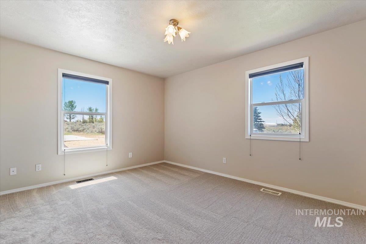 147 East Indian Crk Road Boise, ID 83716 - Photo 22 of 43 Neutral-toned interior featuring two windows with white trim, light-colored carpeting, and a ceiling-mounted light fixture