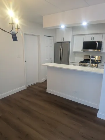 a view of kitchen with stainless steel appliances refrigerator stove microwave and cabinets